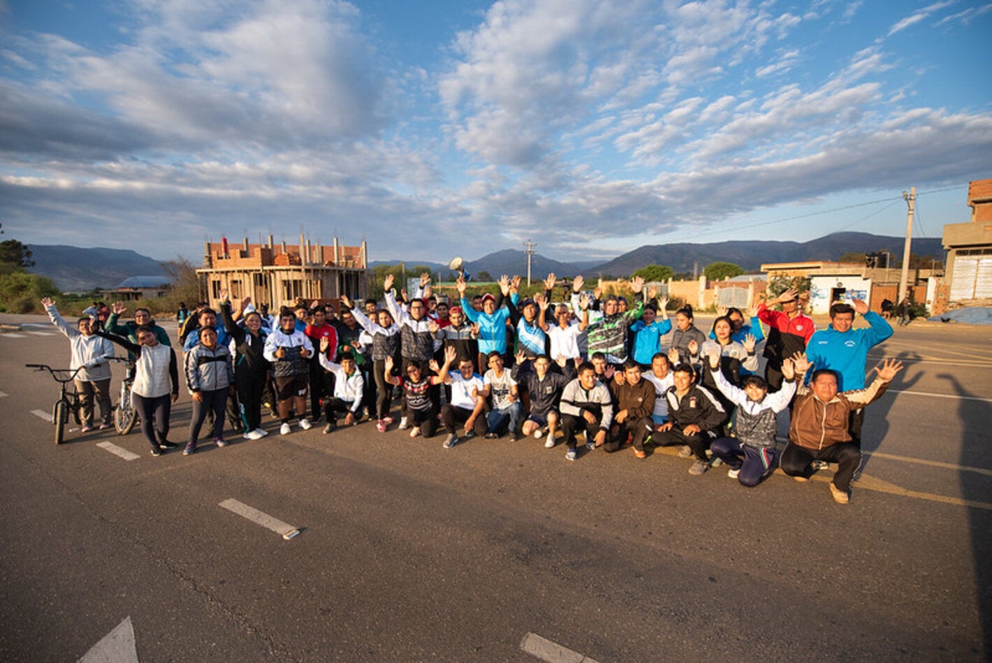imagen de un grupo de personas con las manos levantadas en señar de victoria, en un paisaje rural.