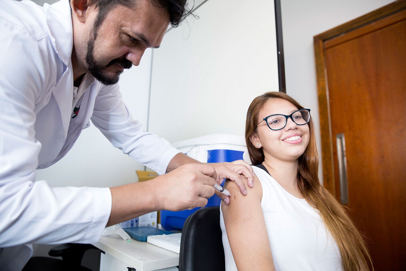 Profissional de saúde aplicando vacina em menina adolescente