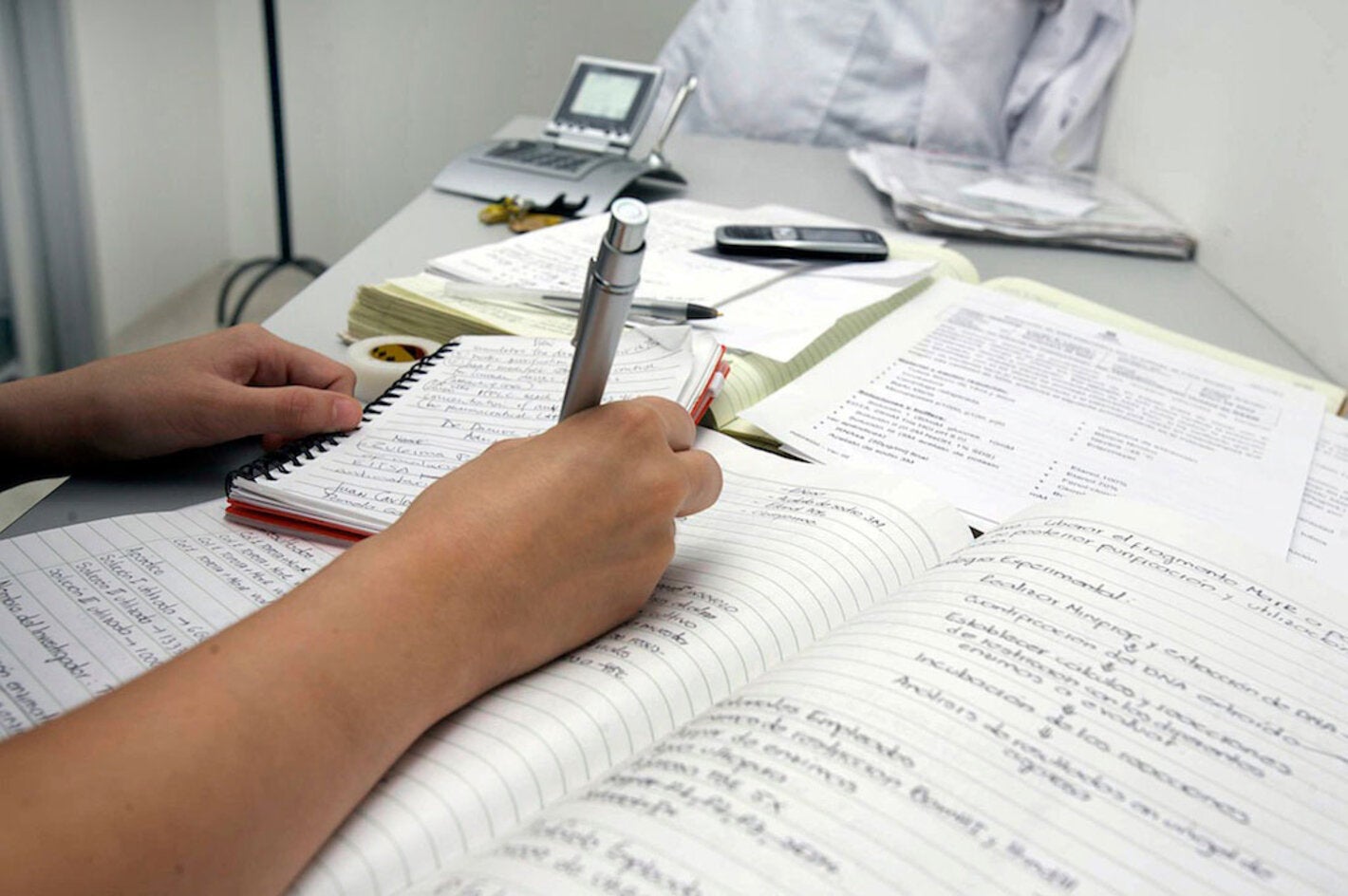 Una persona escribiendo observaciones en un cuaderno.
