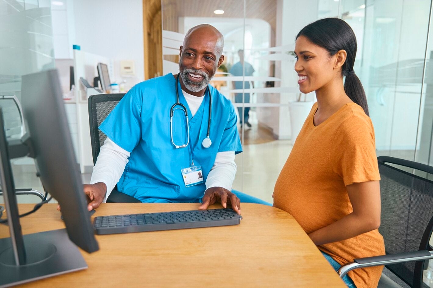 Male doctor and pregnant patient review electronic medical records