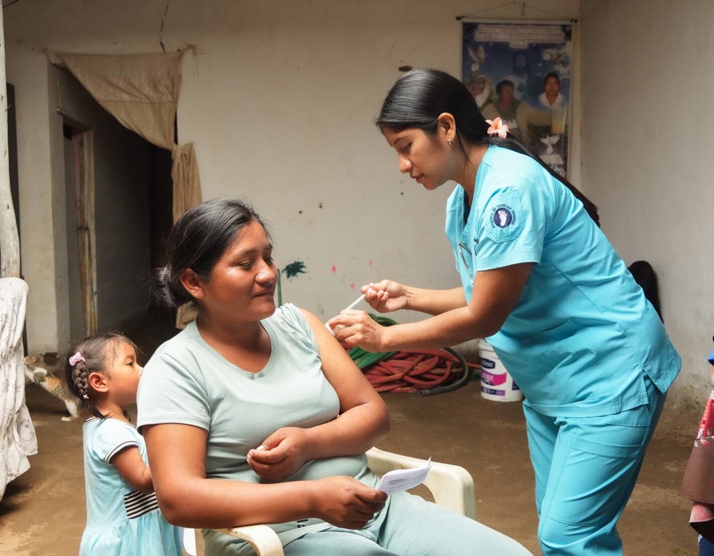 Personal de salud aplica la vacuna a una mujer junto a su hija pequeña
