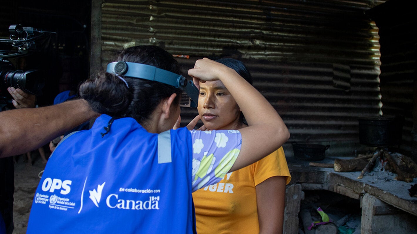 una mujer de OPS realizando atención primaria sobre una mujer de la comunidad