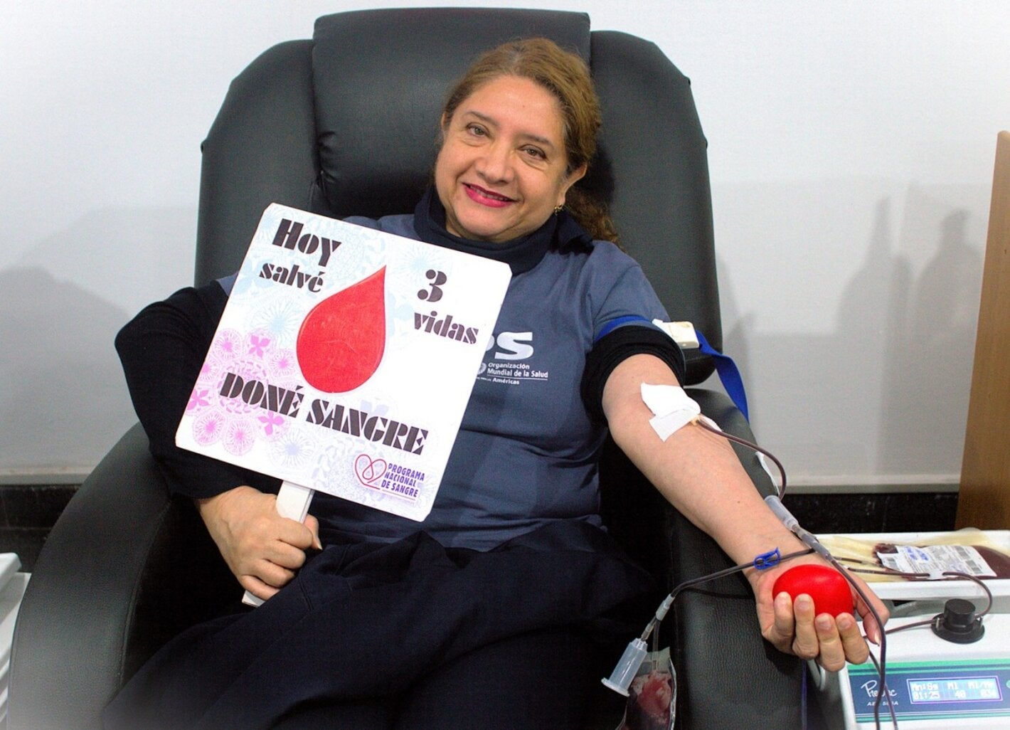 Donante de sangre posa con un rótulo de las vidas salvadas a raíz de la donación