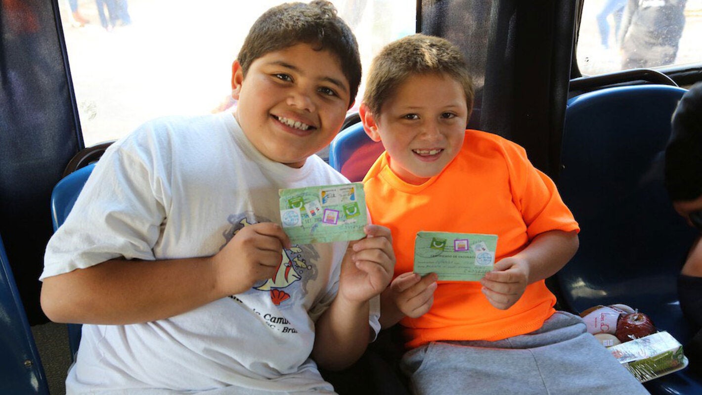 Boys show their vaccination record cards