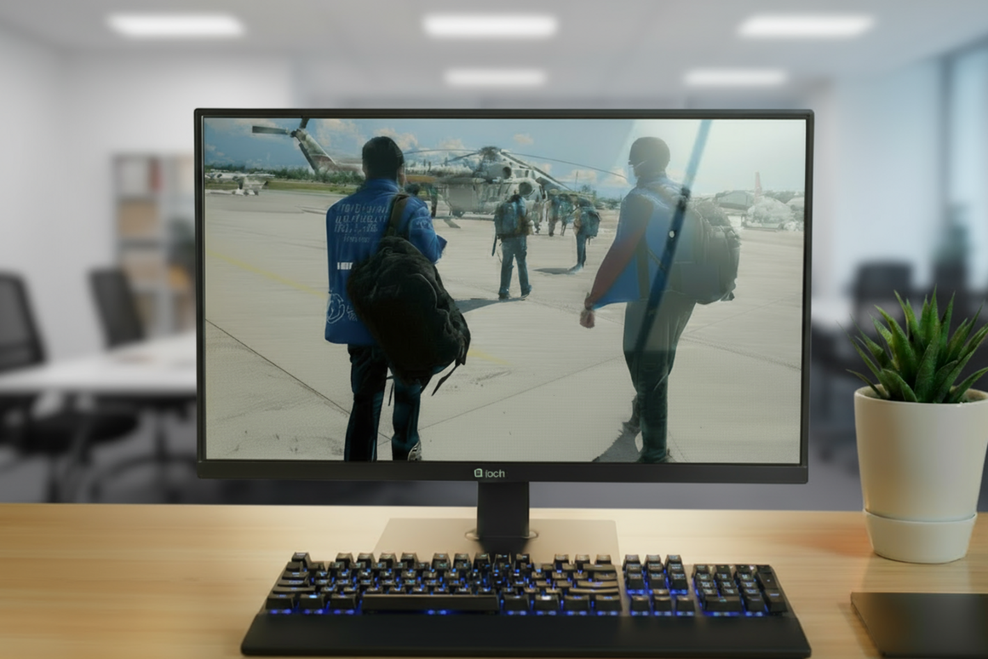 Monitor de computadora con foto de dos hombres con chalecos de OPS, en el fondo se ve un helicóptero