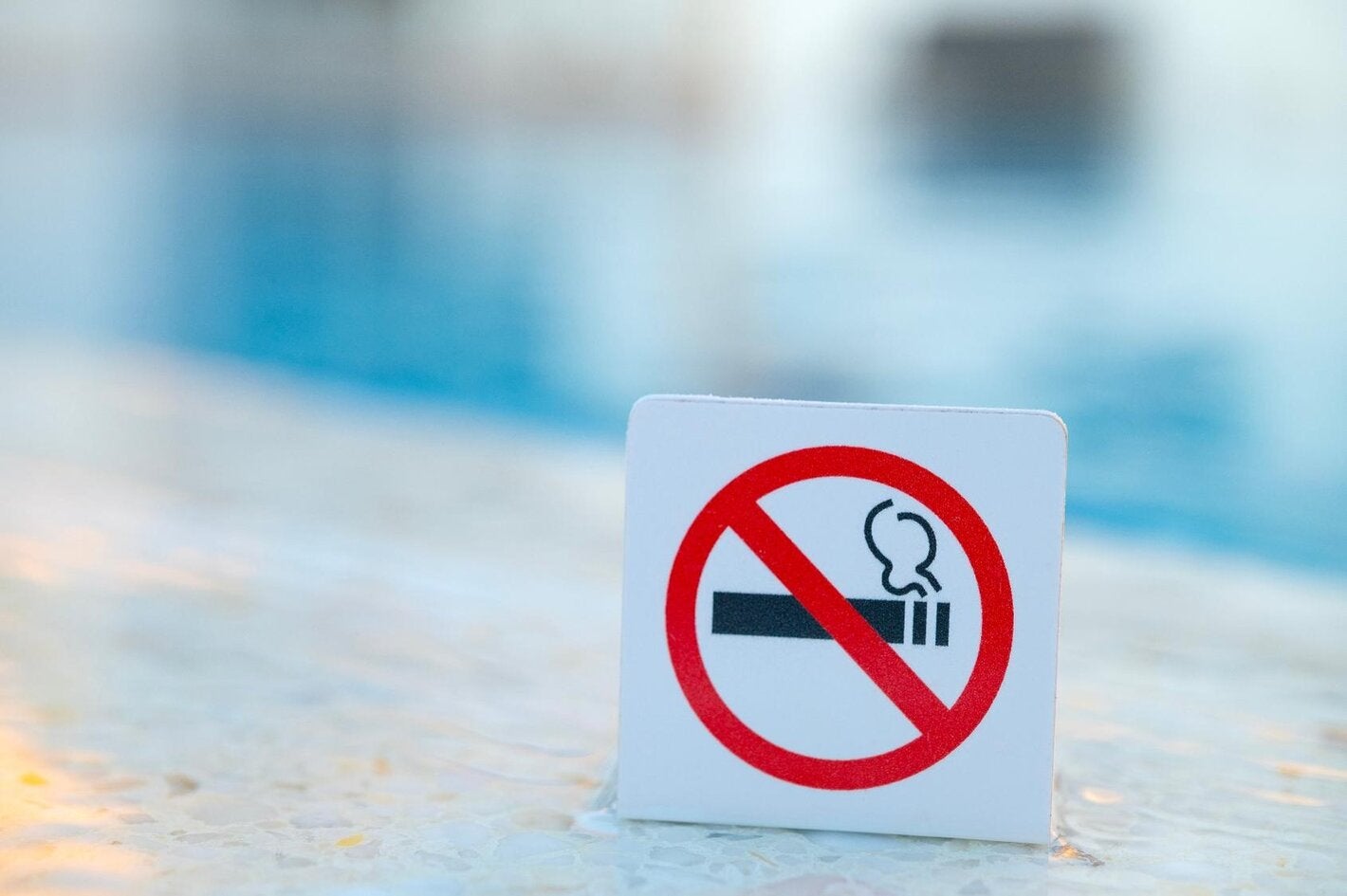 Signo de "no fumar". Está prohibido fumar en lugares públicos. Señal de prohibición cerca de agua azul en la piscina