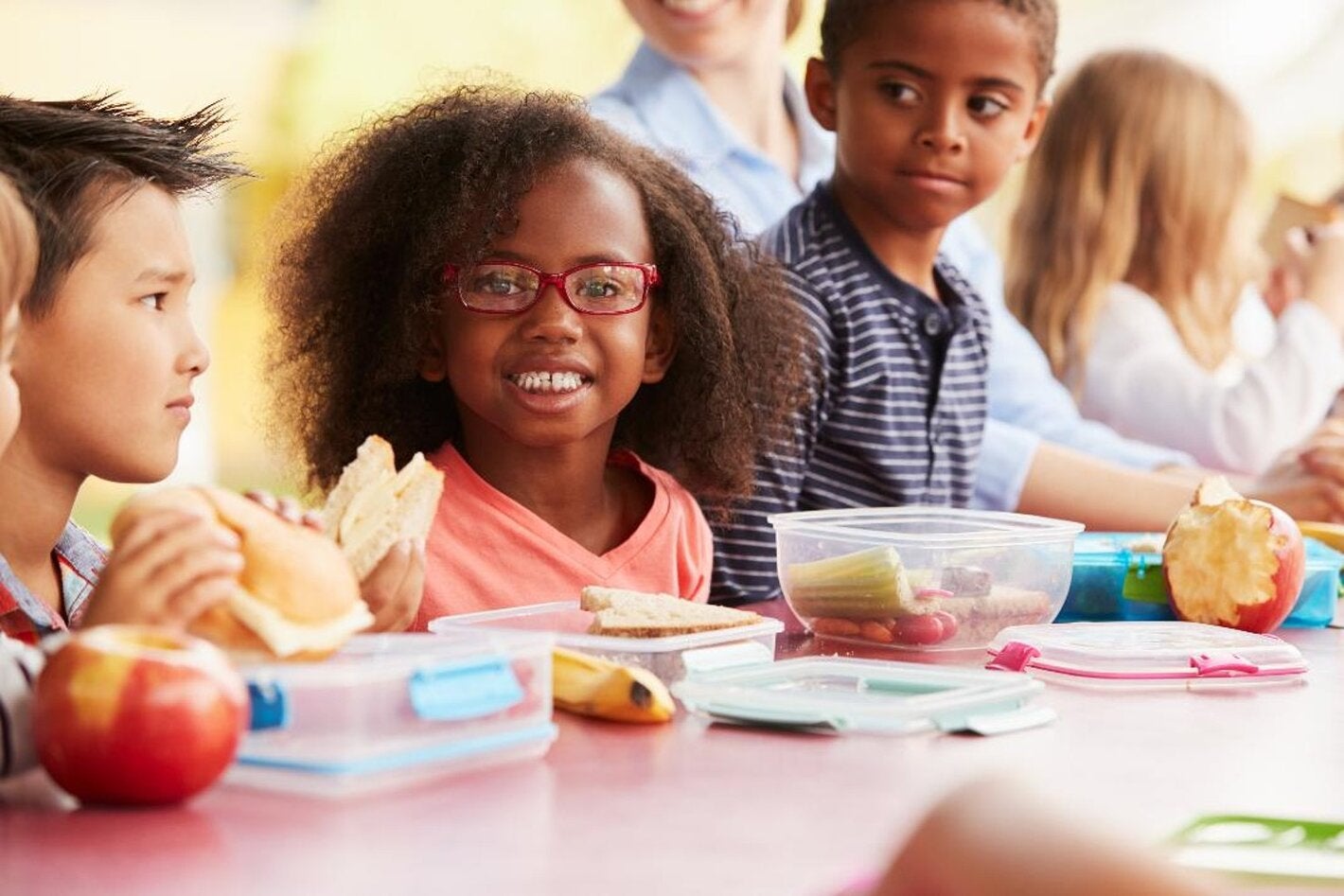 Niños de escuela comiendo juntos manzanas, plátanos y bocadillos