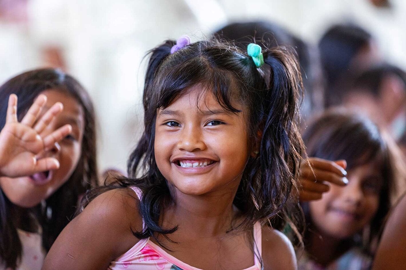Menina sorrindo e acenando para a câmera