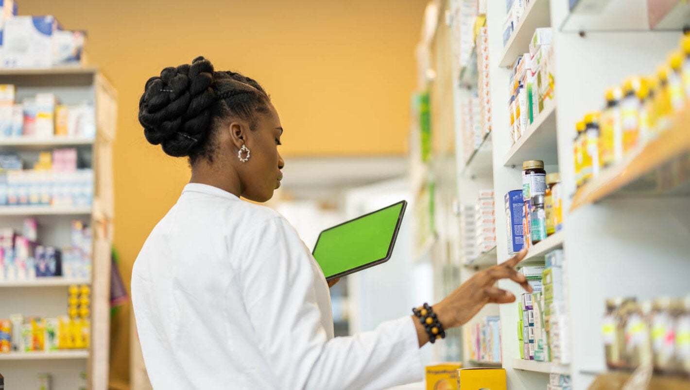 Female pharmacist checking the medicine on shelfs in drugstore