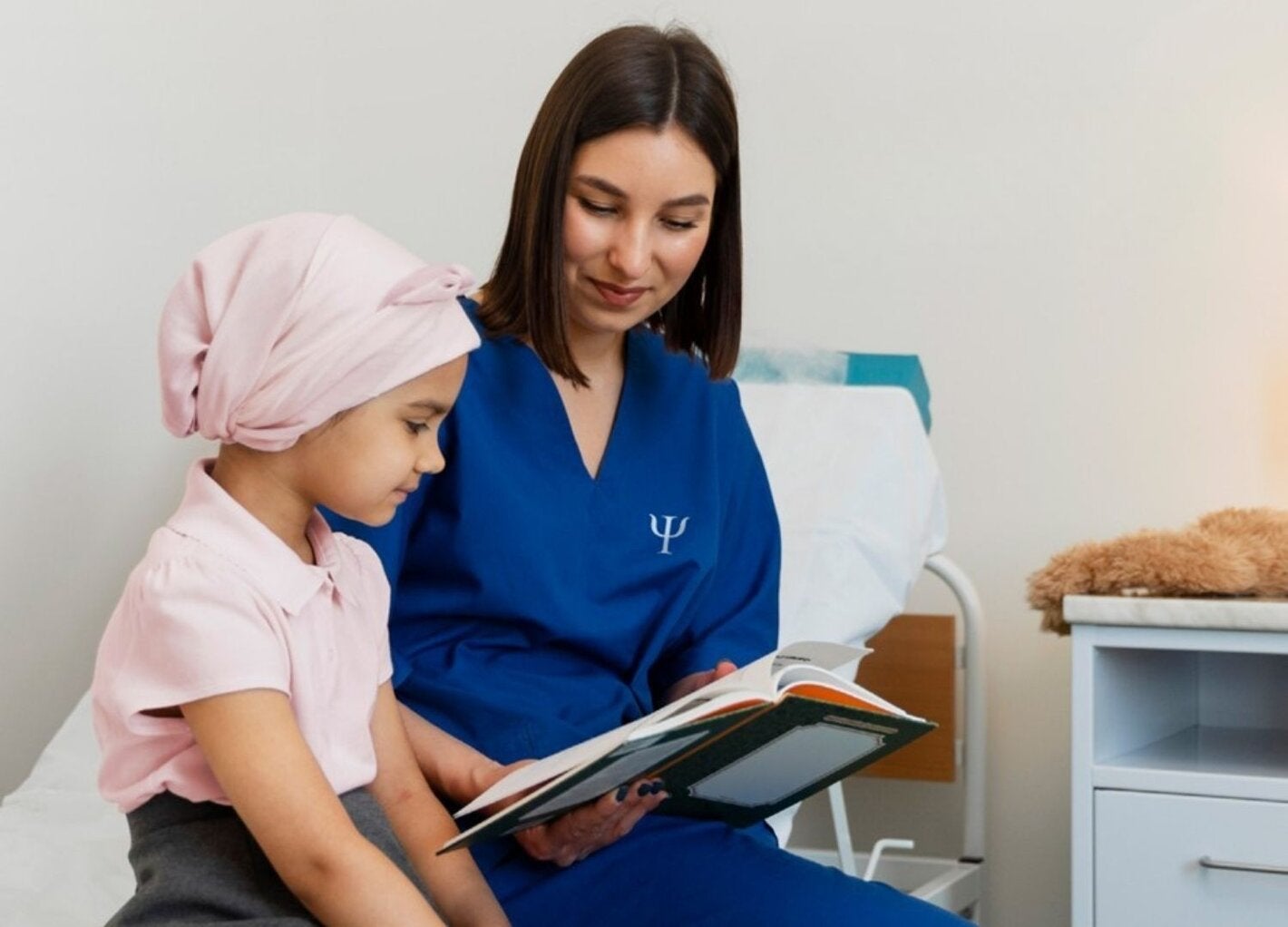 personal de salud mostrándole un libro a una niña con cáncer