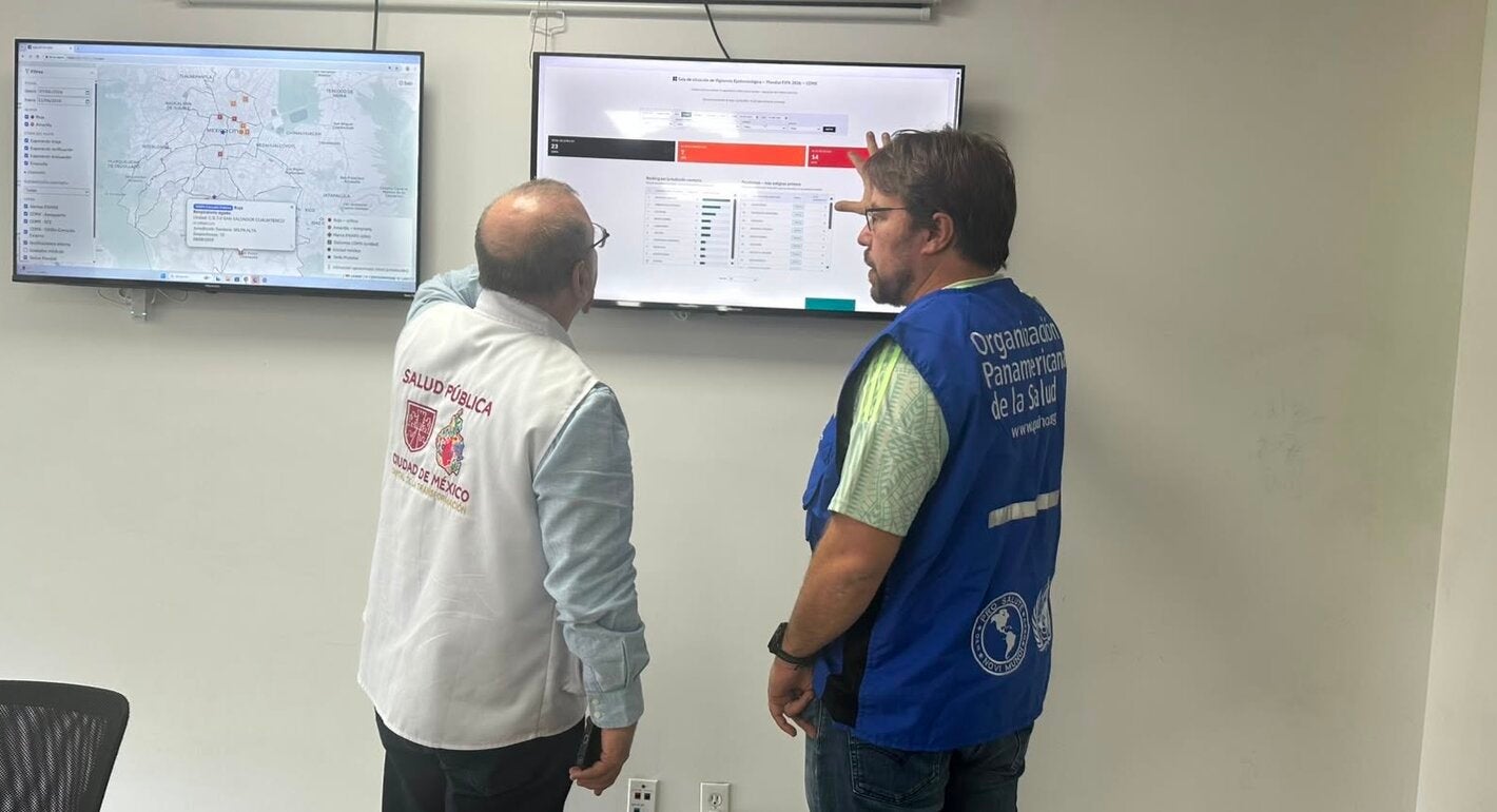 PAHO and MoH staff in front of a screen showing a dashboard