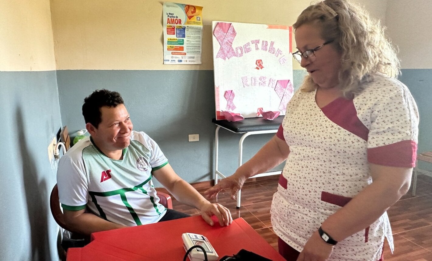 A healthcare worker measures and records a community member’s blood pressure at a health facility in Paraguay.
