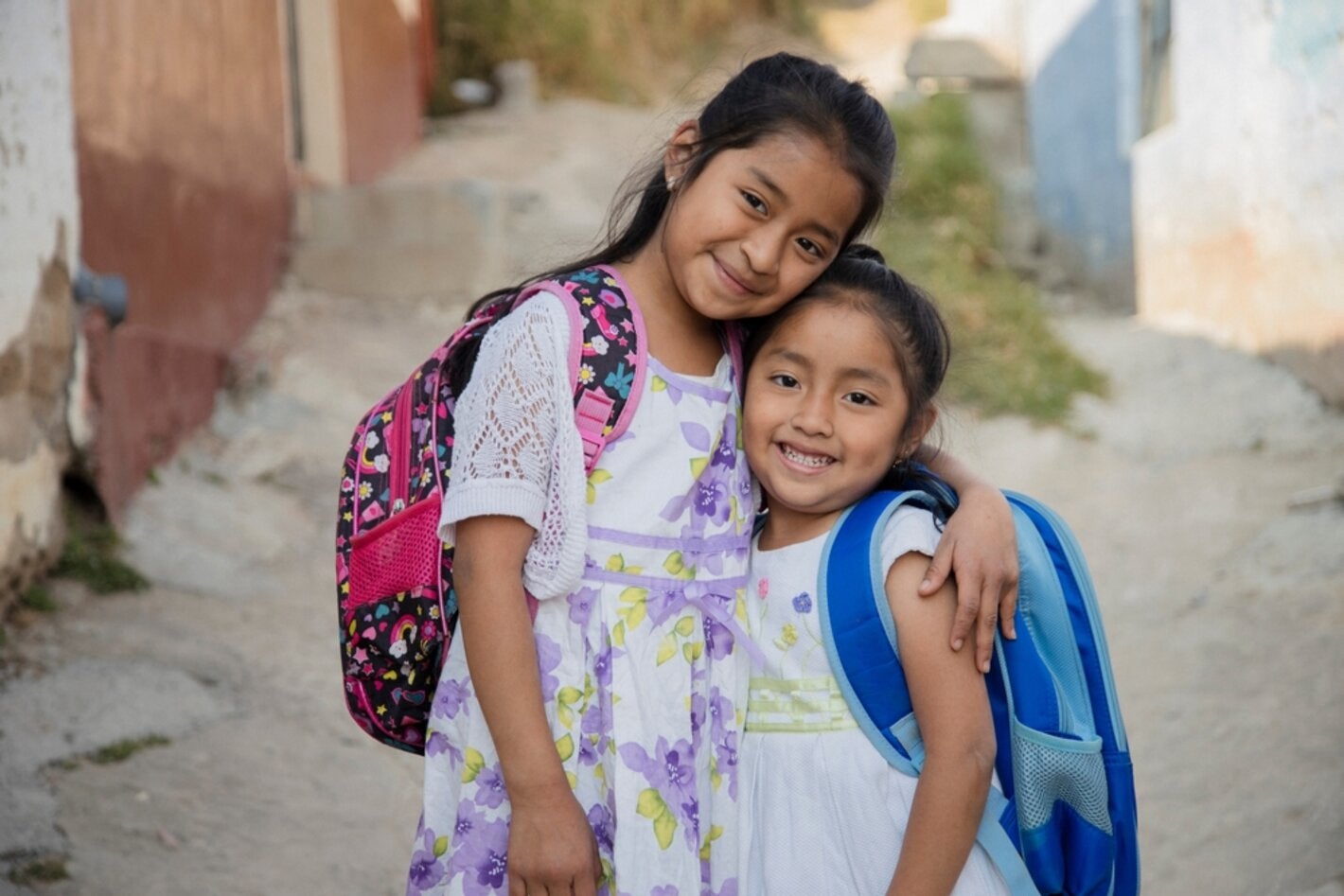 Dos chicas abrazadas con sus mochilas