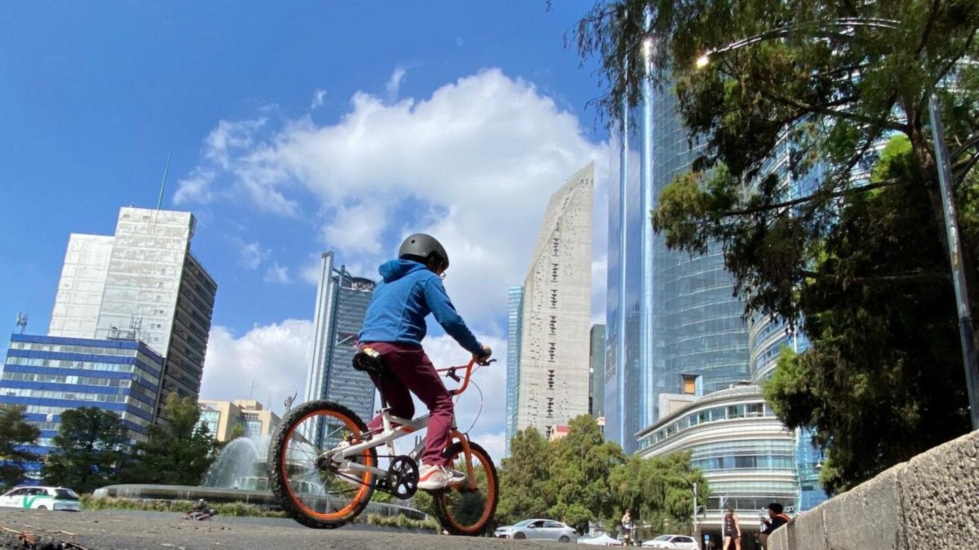 Niño en bicicleta en Ciudad de México con un cielo azul