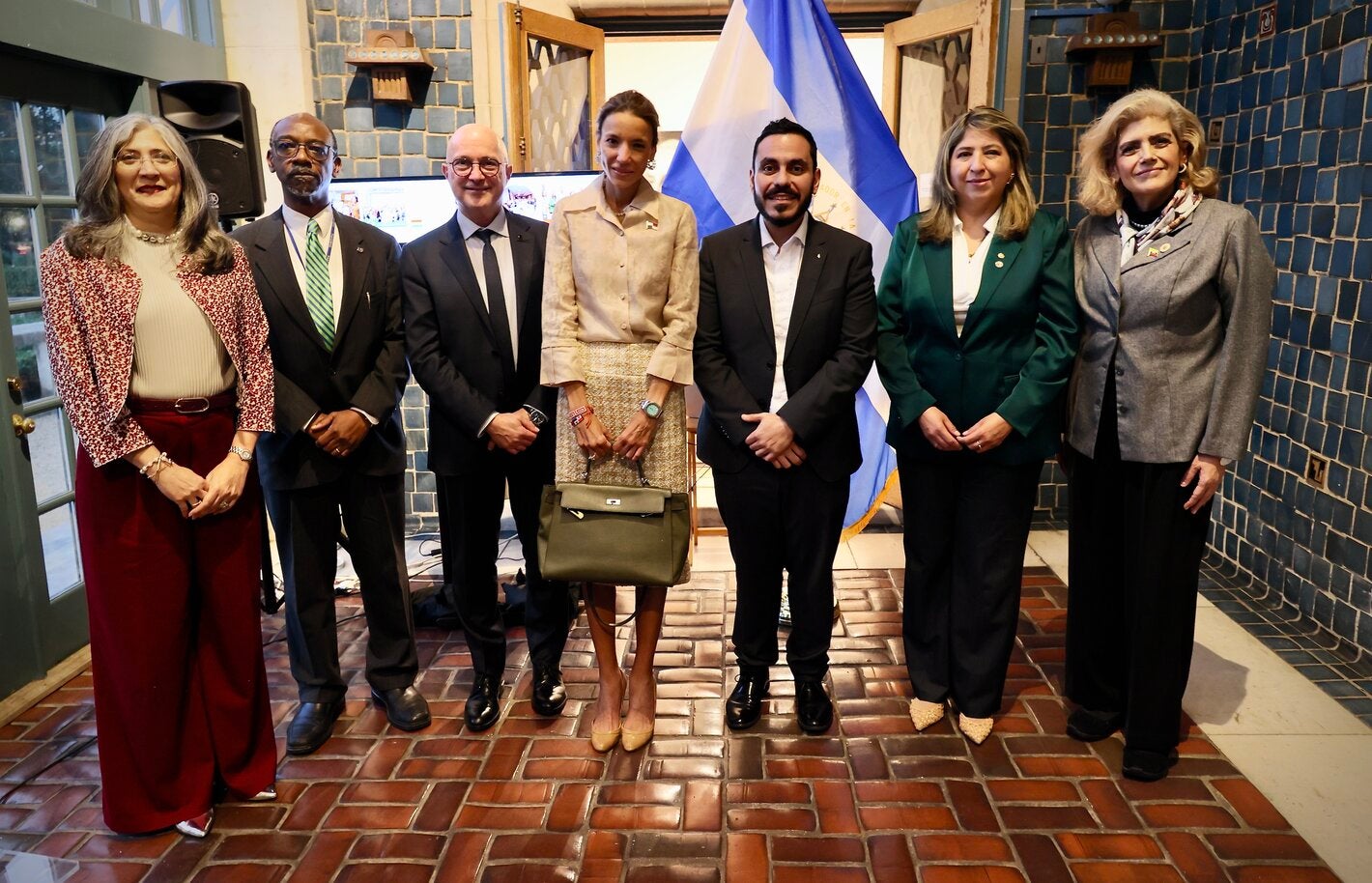 siete personas paradas en frente de la bandera de El Salvador
