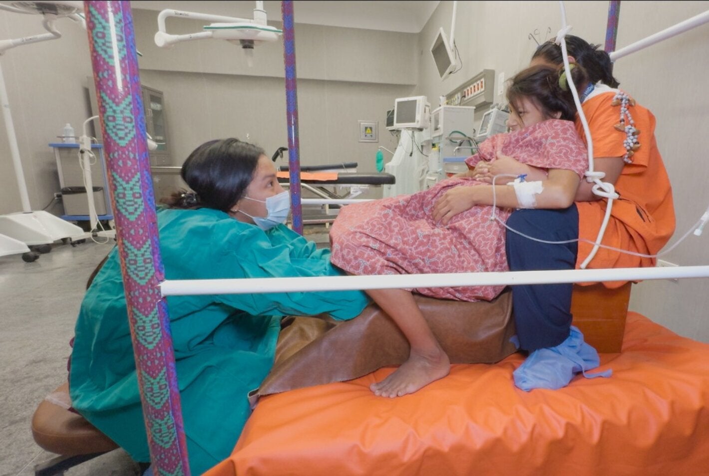 Mujer en trabajo de parto asistida por dos profesionales de la salud en el Hospital Intercultural de Atalaya, en Ucayali, Perú