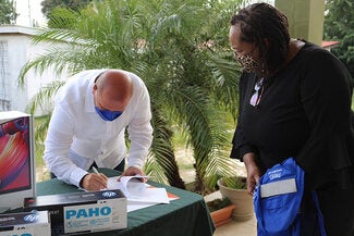Minister signing handover documents from PAHO
