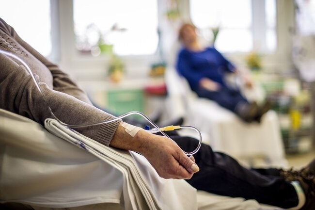 Chemoteraphy room with the arm of a patient with an IV in close up and a blurred second patient in the background