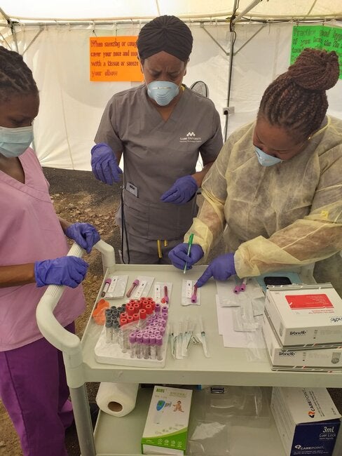 Los trabajadores de la salud en Dominica que usan mascarillas protectoras se concentran en etiquetar las muestras de prueba.