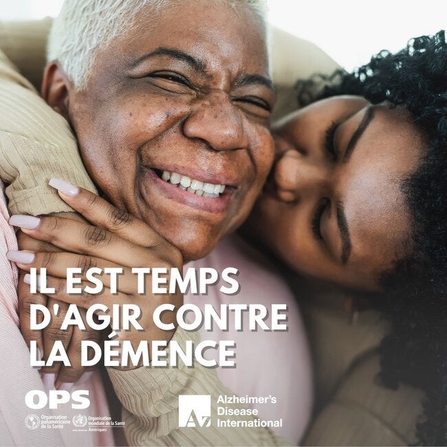 Une jeune femme enlace par derrière une femme plus âgée souriante et l'embrasse sur le visage.