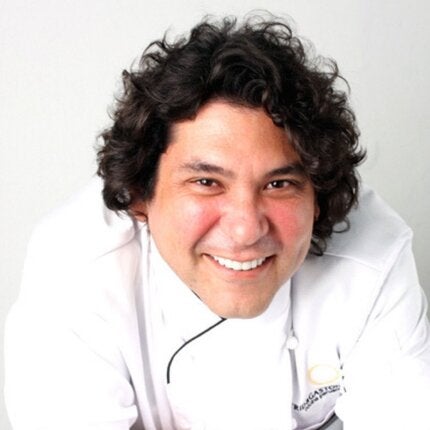 Gaston Acurio in white chef attire smiling at the camera
