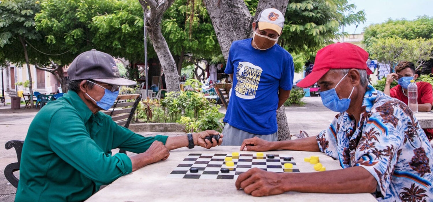 Señores jugando tablero con medidas preventivas