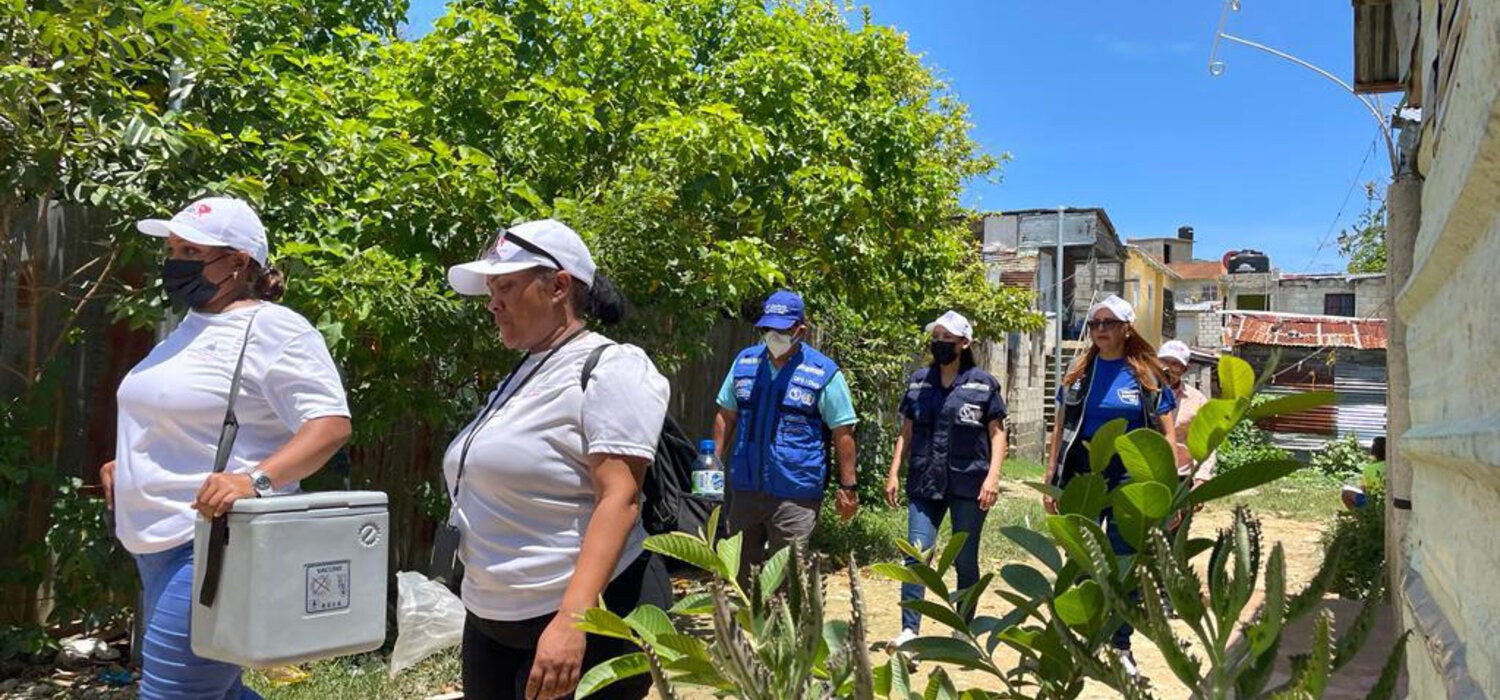 Health workers carrying vaccines in coolers to remote areas