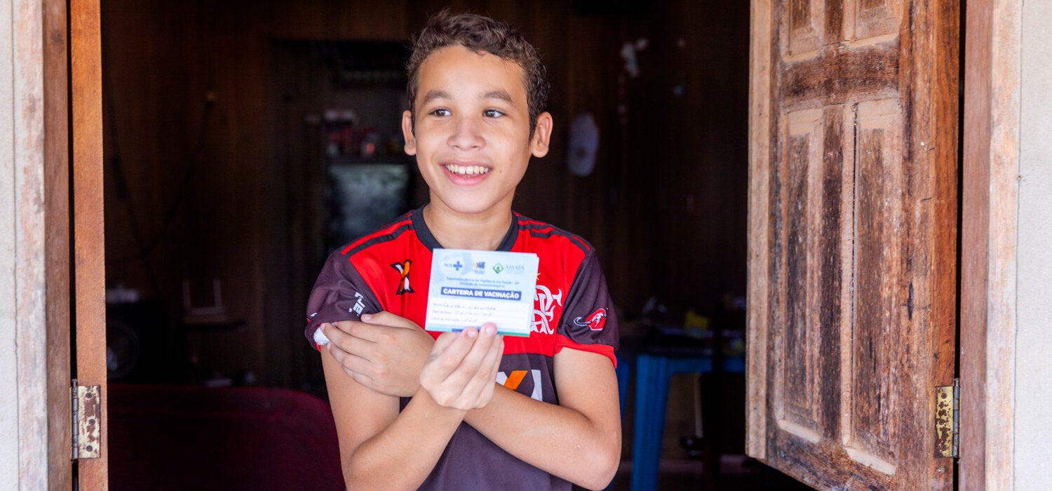 Menino vacinado com a caderneta de vacinação na mão