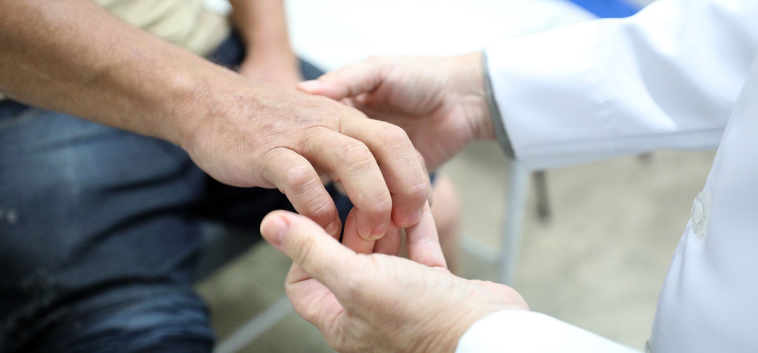 Profissional de saúde examina mãos do paciente