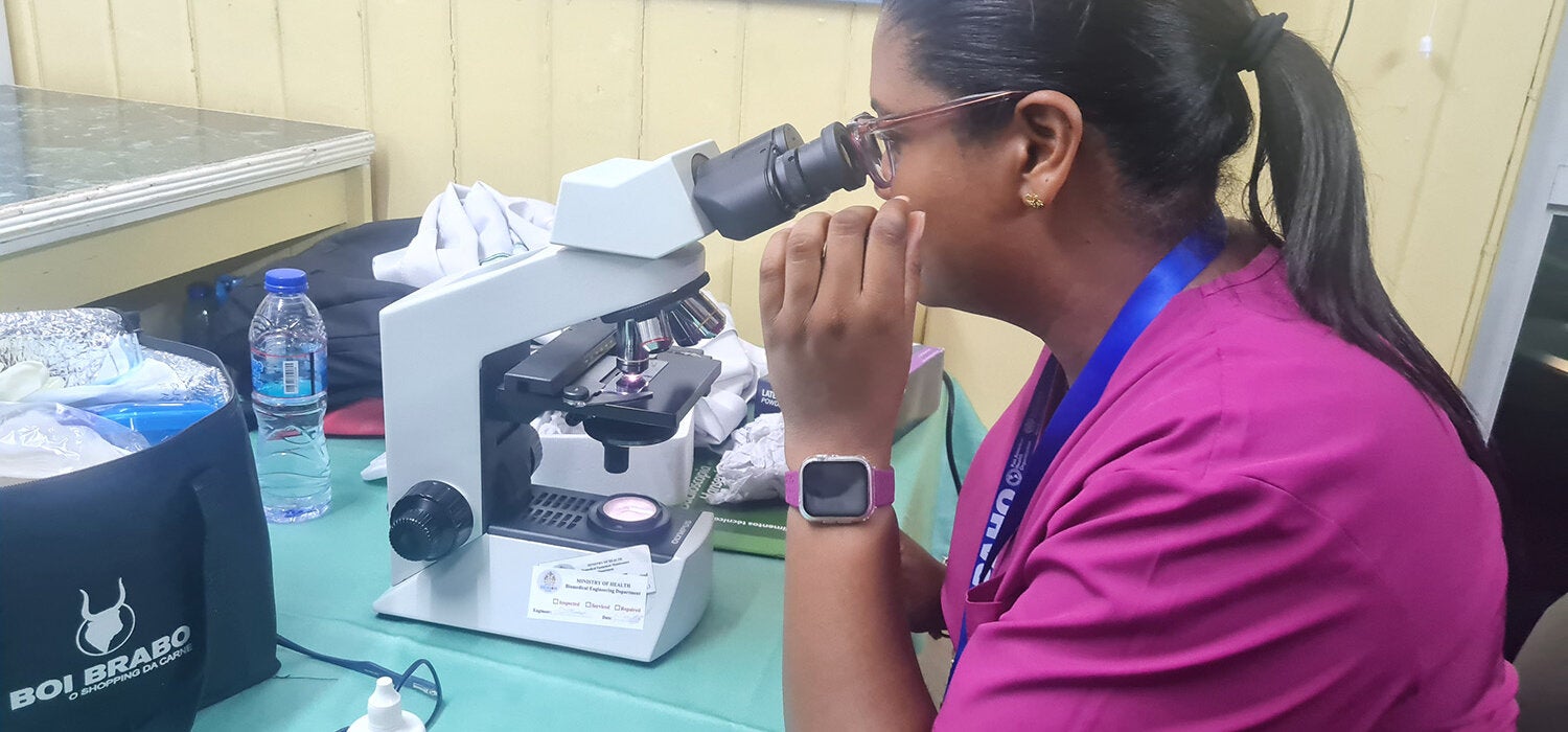 woman looking through microscope