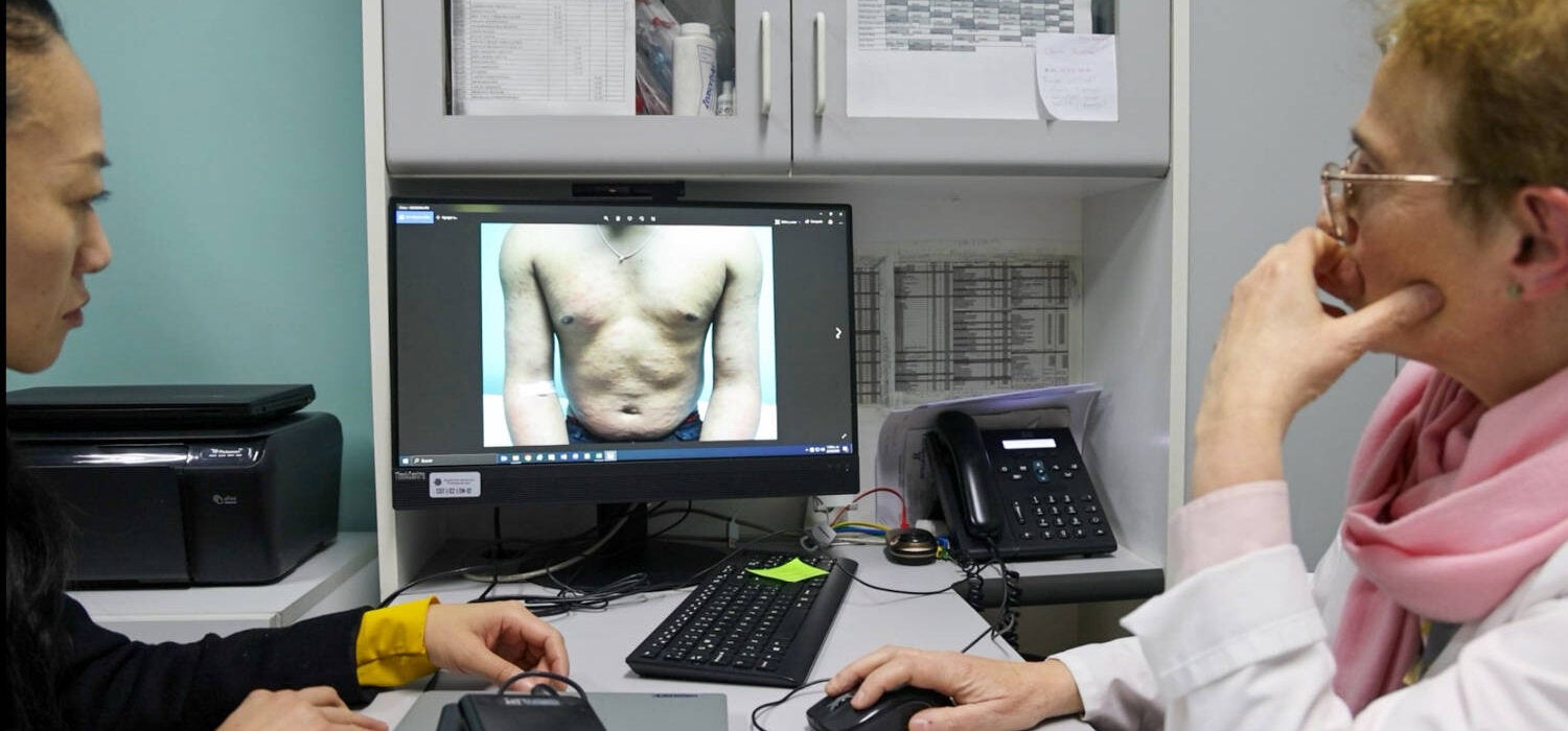two technicians study patient torso on screen