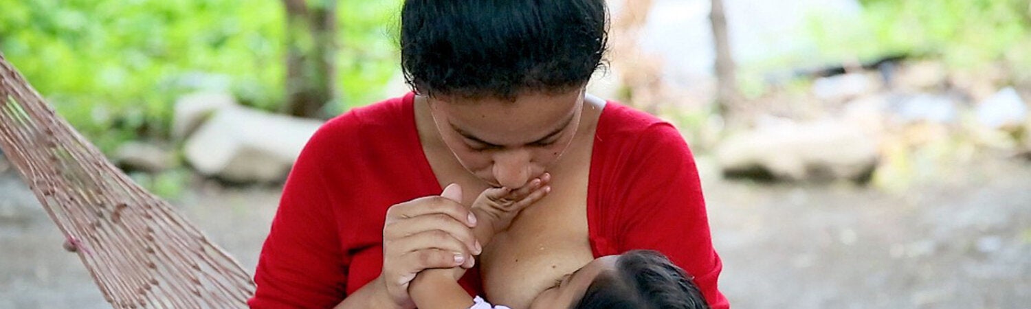 Mother holding and breastfeeding her child outside on a hammock