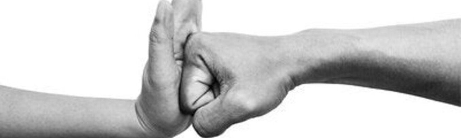 Foto de una mano con la palma extendida deteniendo el golpe de un puño cerrado con otra mano