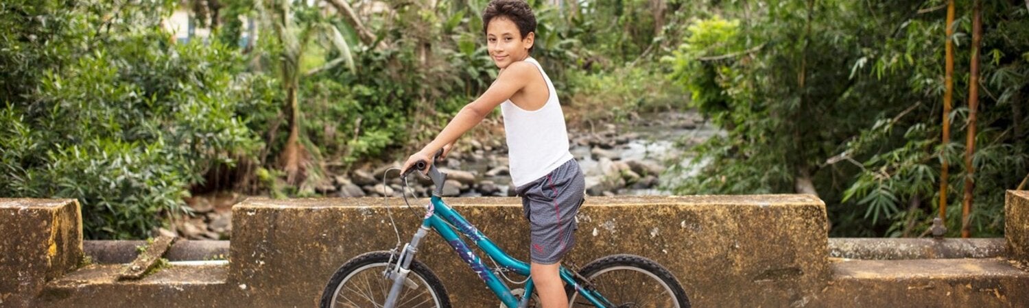 Niño de unos 11 años sentado sobre una bicicleta mirando a la cámara