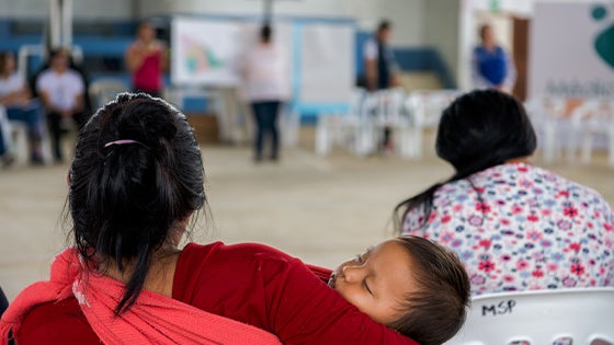 Woman holding child in community forum 